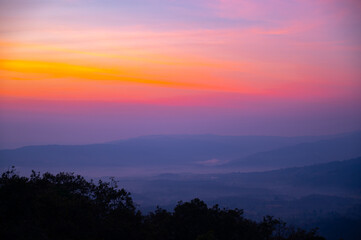 Obraz premium Layer background of Aerial view sunset , sunrise over dark mountain with fog over the ground.The early evening sun illuminates the mountains and valleys.