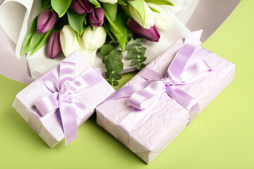 Gift boxes and bouquet of beautiful tulip flowers on green background. Hello spring
