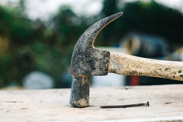 Using rusty hammer and nail on wood and blur background. Tools of wood work. Detail of a nail and a...