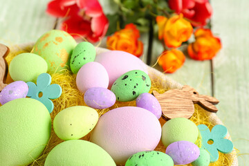 Fototapeta na wymiar Basket with painted Easter eggs and decor, closeup