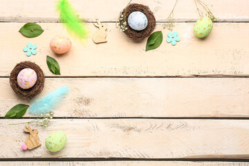 Composition with Easter eggs, feathers, plant leaves and gypsophila flowers on light wooden background