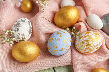 Beautiful Easter eggs and gypsophila flowers on fabric background, closeup