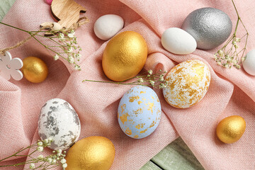 Beautiful Easter eggs and gypsophila flowers on fabric background, closeup