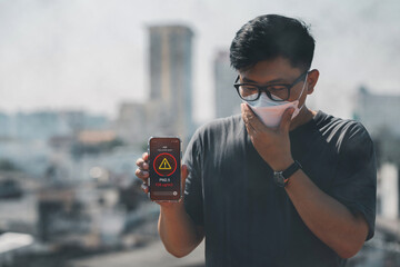 Man wearing the N95 Respiratory Protection Mask and using a smartphone app showing PM 2.5 dust in...