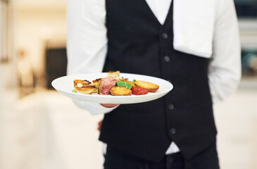 Plate, restaurant server and hand with food for luxury fine dining, nutrition and service in night. Waiter man, hospitality services and dinner at kitchen, diner and holding cuisine meal in workplace - obrazy, fototapety, plakaty