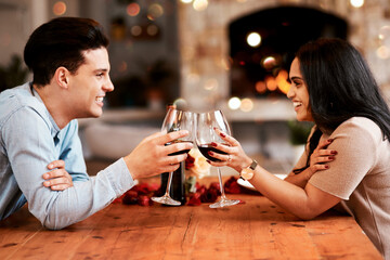 Love, wine and couple cheers on valentines day date at home with smile, romance and bokeh. Date night, man and woman at table in living room, valentine celebration and happy relationship together.