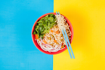 Instant noodles ramen soup on bowl and chopsticks on colored background