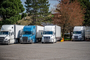 Industrial long haul big rigs semi trucks with loaded semi trailers standing in row on the truck stop parking lot for truck drivers rest © vit