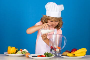 Chef kid boy making fresh milk shake smoothie for healthy eat. Portrait of little child in form of cook isolated on grey background. Kid chef. Cooking process.