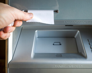 a man takes a check issued by an ATM, a check without inscriptions, a place for the text on the...