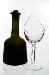 Transparent broken glasses and a dark bottle of wine.