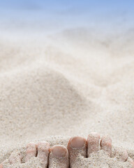 Fototapeta na wymiar Summer rest or vacation on beach concept. Woman toes close up buried in sand on seashore. Female bare feet with natural toenails on white beige sand. Selective focus, blurred background