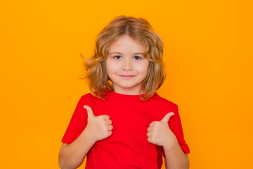 Child showing thumbs up on studio isolated background. Portrait of kid boy making thumbs up sign. Happy kid, happy and smiling emotions.