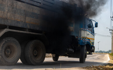 A loaded truck travels on the road with thick black smoke from the exhaust