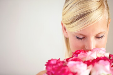 Fototapeta premium Smelling, floral and woman with flowers as a gift isolated on a grey studio background. Surprise, romantic and girl with a bouquet of roses for valentines day on a backdrop with mockup space