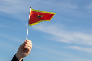 Montenegro flag in hand flutters in the wind against the sky