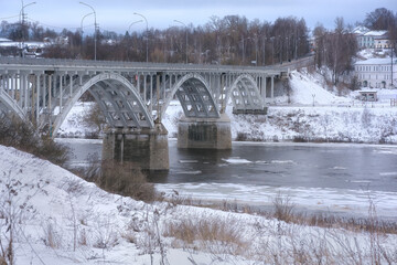 View of the Staritsky Bridge across the Volga River in winter. Ice drift on the Volga river. Winter landscape.