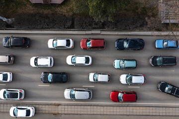view from above of a traffic jam at a road intersection. aerial drone flight with a busy city in the background and rush hour traffic, seen from above a highway.