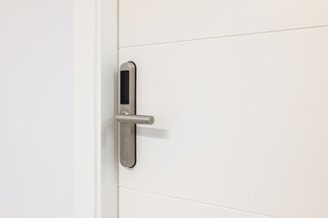 Naklejka premium Closeup of an electronic mortise lock with copy space on white door. An electronic unit with display is built into metal handle. Opening doors with plastic card with microchip or digital code.