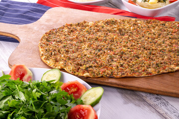 Turkish pizza lahmajun with minced lamb and beef on a thin crust with vegetables and herbs, Wooden table, top view, flat lay, copy space