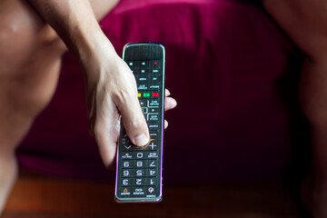 Close-up of a person changing the television with the remote control in quarantine period