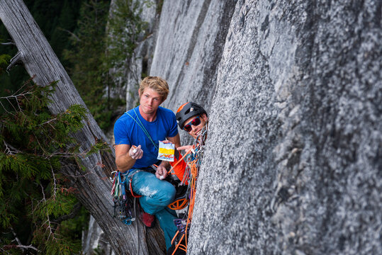 two climbers looking funny at camera with candies while rock climbing
