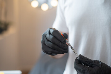 Man's hands in black gloves hold syringe for cosmetic injections. space for copy text. Person in...