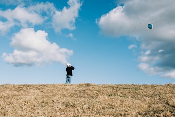 young boy flying a kite on a hill on a beautiful sunny day