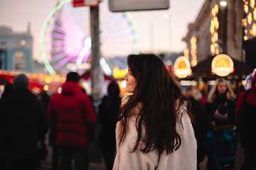 Happy teenage girl walking in Christmas market in evening city