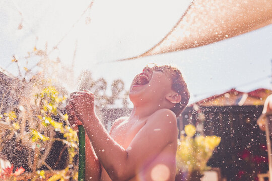 Big smile playing with a hose on a hot day