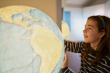 Smiling girl examining shining globe