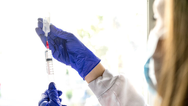 Midsection Of Female Nurse Holding Syringe Against White Background