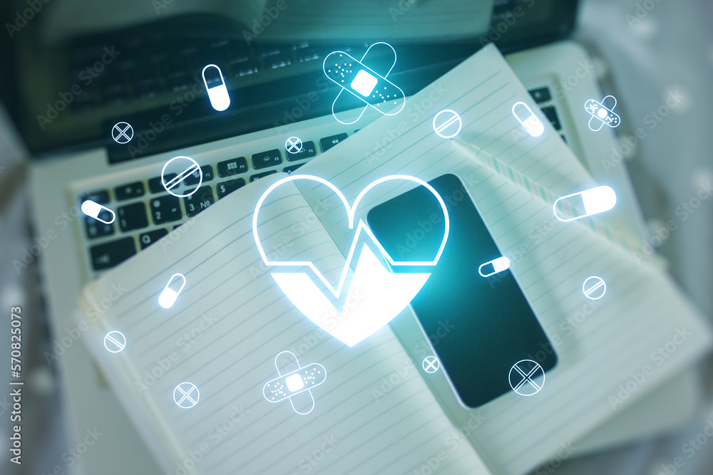 Poster top view of desktop with laptop, book and smartphone with glowing heart hologram on blurry backgroun