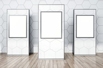 Front view on three blank white advertising posters with place for your logo or text on light grey stands polygonal printed in abstract hall with wooden wall background. 3D rendering, mock up