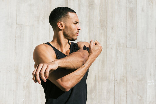 Upper part of African American male athlete stretching arms