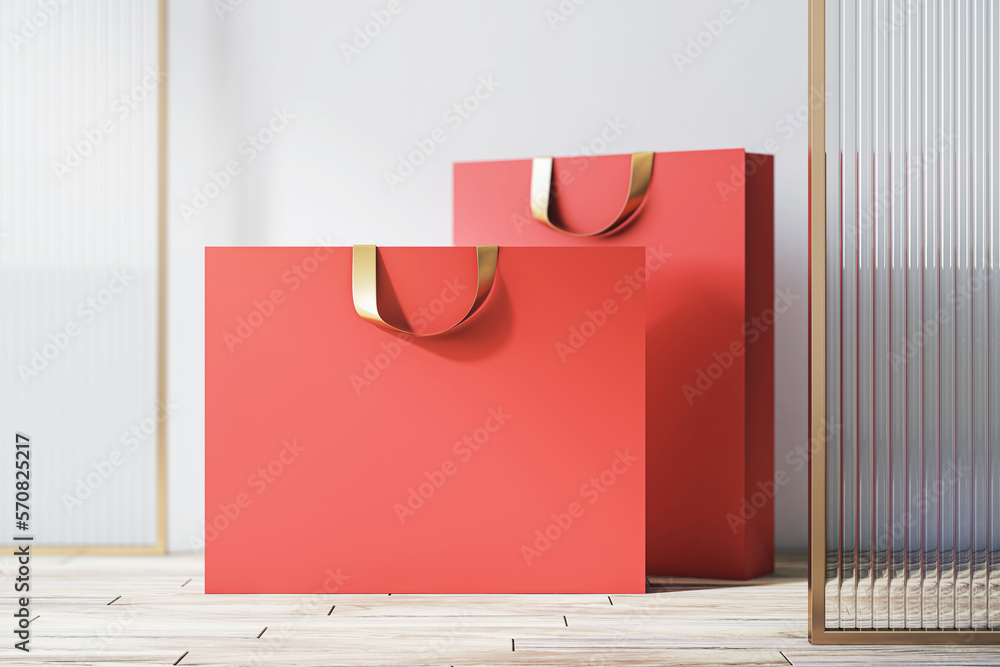 Aufkleber front view on blank red paper shopping bags with place for your brand name or text on light wooden f