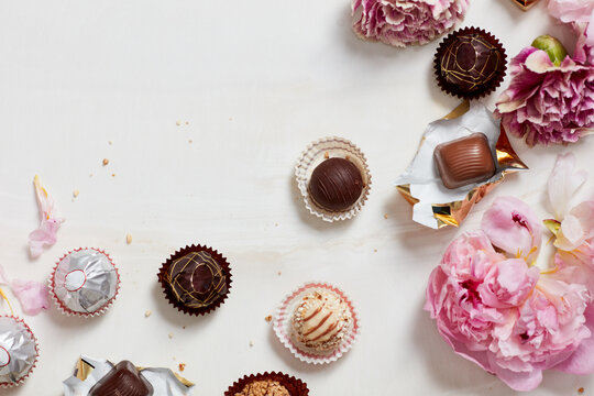 Still Life Of Open Chocolates And Wrappers With Flowers