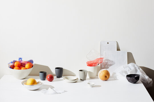 Still life with fruits, pottery cups and surfaces