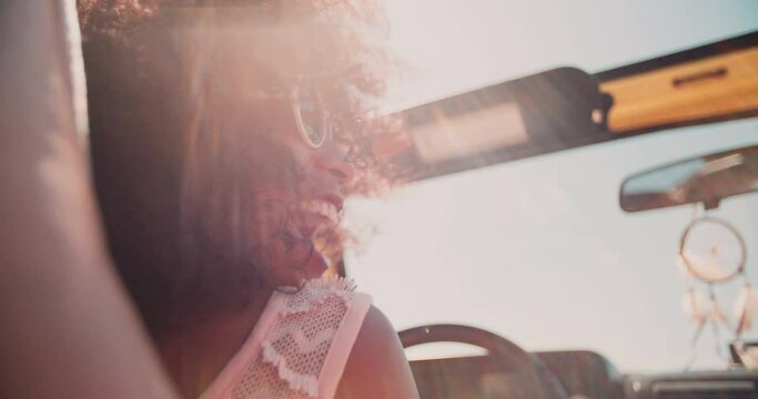 Smiling Afro girl driving in an open top vehicle while on a road trip for summer vacation in Slow Motion
