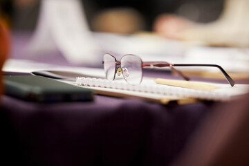 women's glasses with diopters lie on a notebook on the table. Iron-framed glasses, pen, notebook...