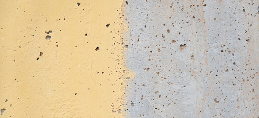 Abstract light yellow painted and gray plaster wall background. Old stucco sufface wall background with streaks of paint and paint sprays