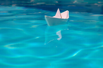 Sailing yacht concept, paper ship with sailing boat. White paper boat into the clear sea water.