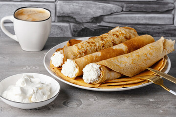 Thin pancakes with cottage cheese with sour cream and coffee. Healthy traditional breakfast concept