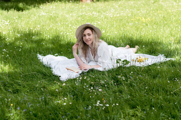 Girl in a hat, lying on a blanket.