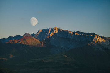 Moon rising behind high mountain peaks at sunset, Pyrenees