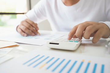 Business man Using calculator analyzing investment chart on the 