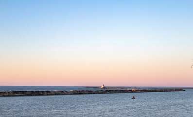 Fototapeta na wymiar Pink sunset over lake with lighthouse in distance