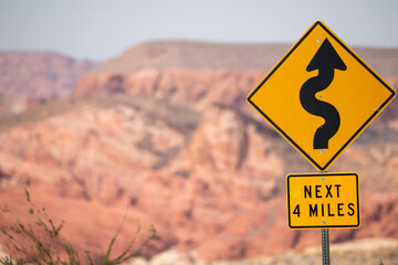 Road sign explaing that next four miles comes winding road - obrazy, fototapety, plakaty