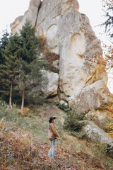 Fototapeta na wymiar woman in a jacket and hat walks through the woods near the mountains