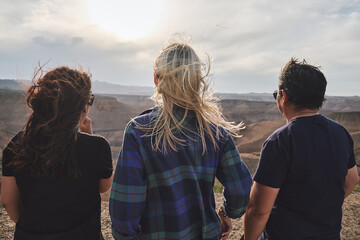 Three people looking to the Grand Canyon from a viewpoint, windy